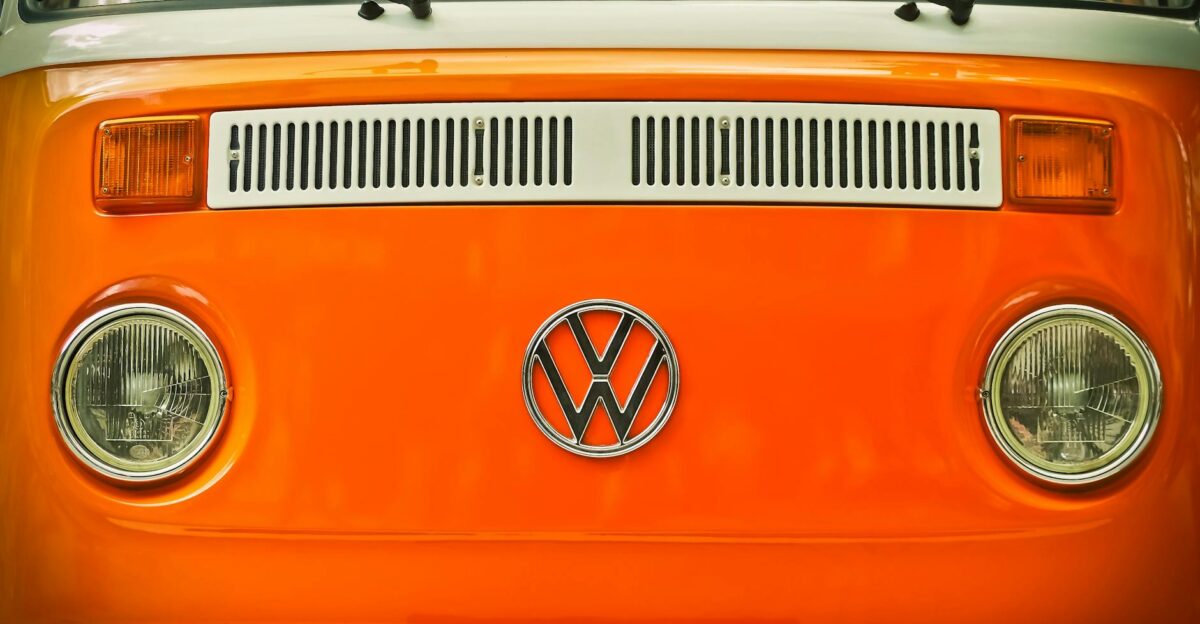 Close-up of a vintage Volkswagen van s front emblem with bright orange color and classic design