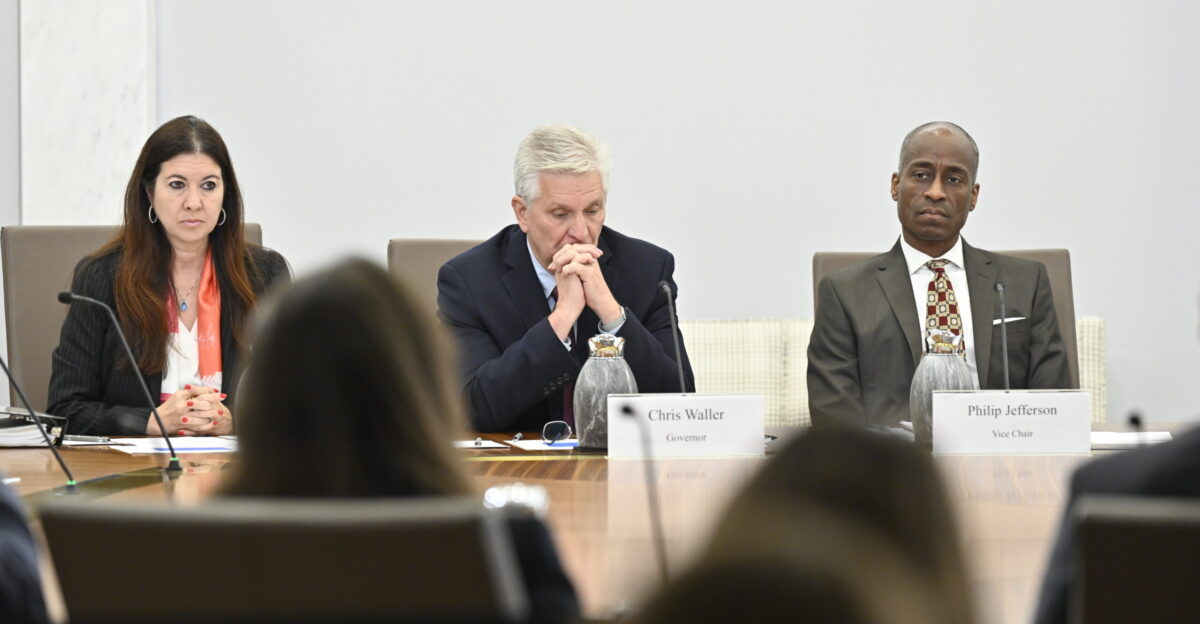 Board members listen to staff present at an open meeting on proposed revisions to the Board s debit interchange fee cap
