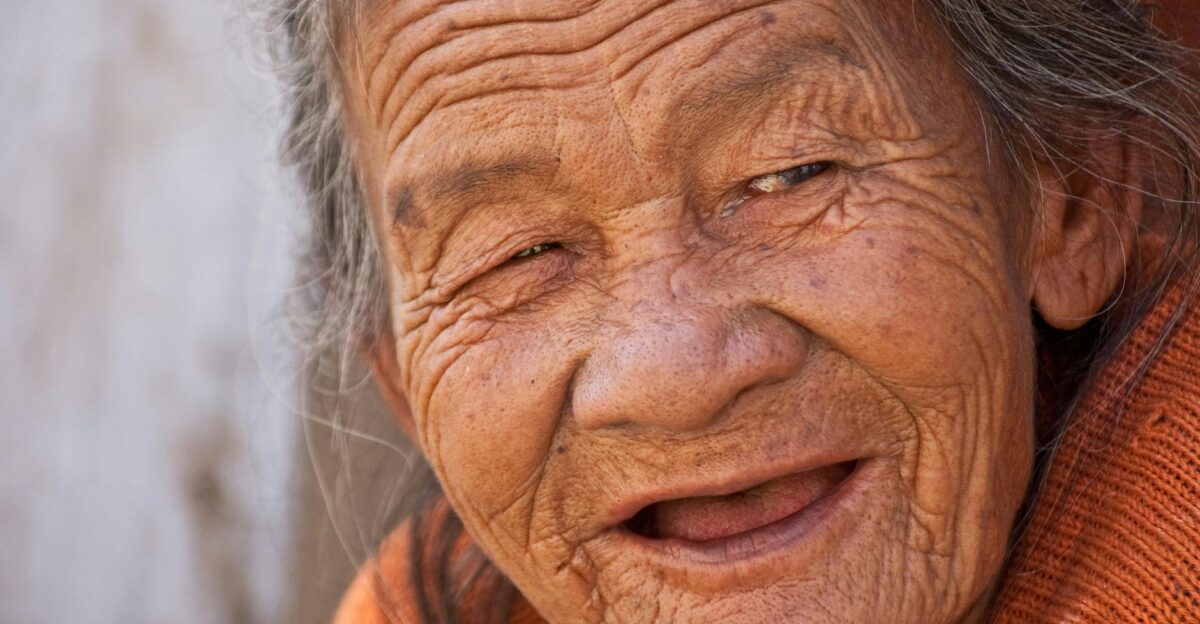 A heartwarming close-up portrait of a smiling elderly woman with deep wrinkles and joyful expression