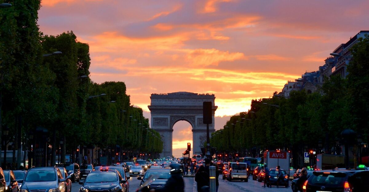 Vivid sunset sky over Arc de Triomphe capturing Parisian traffic and architecture