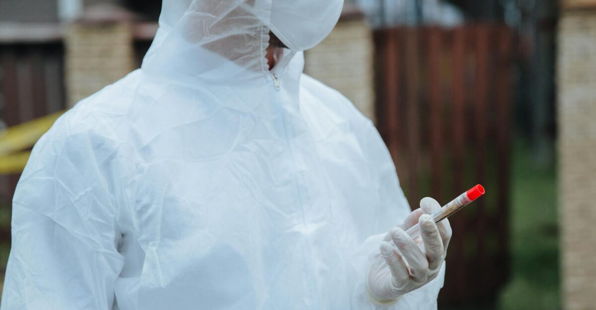 Healthcare professional in protective gear holding a test sample outdoors