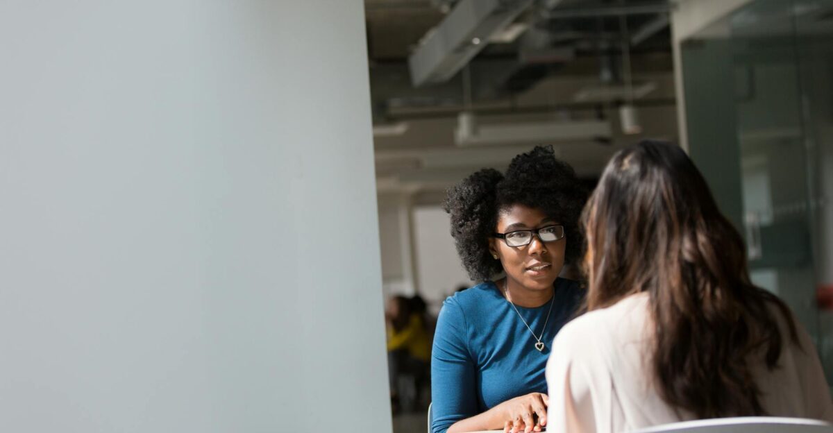 Two women engaged in a discussion in a modern office environment highlighting communication and interaction