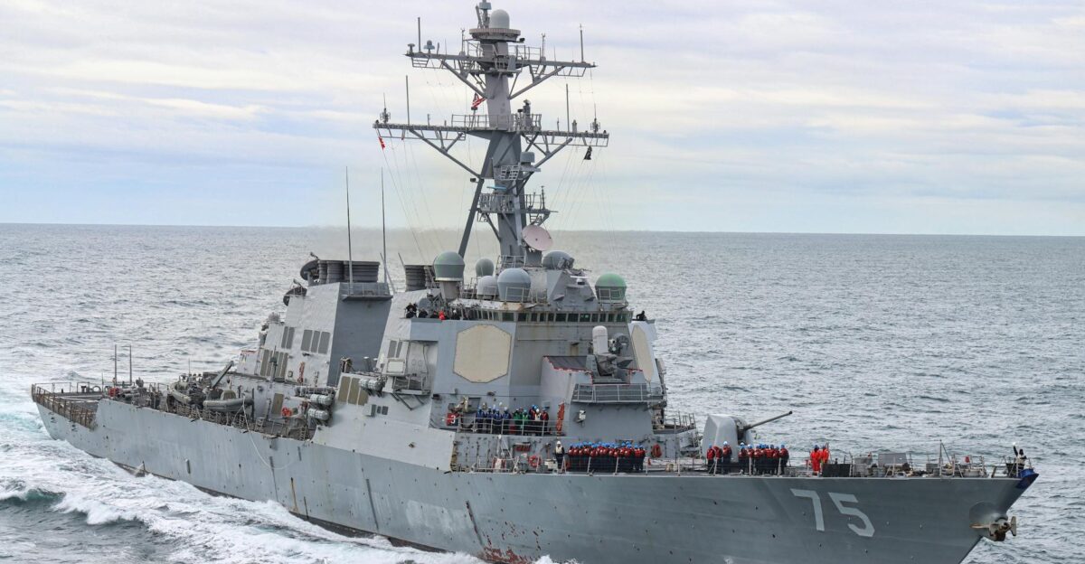 USS Donald Cook warship sailing with crew onboard in open ocean under a cloudy sky