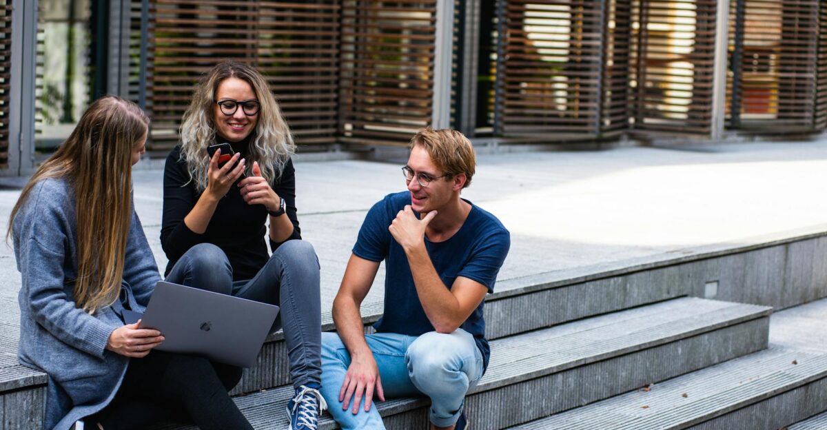 Three young professionals having a friendly chat while sitting on outdoor steps