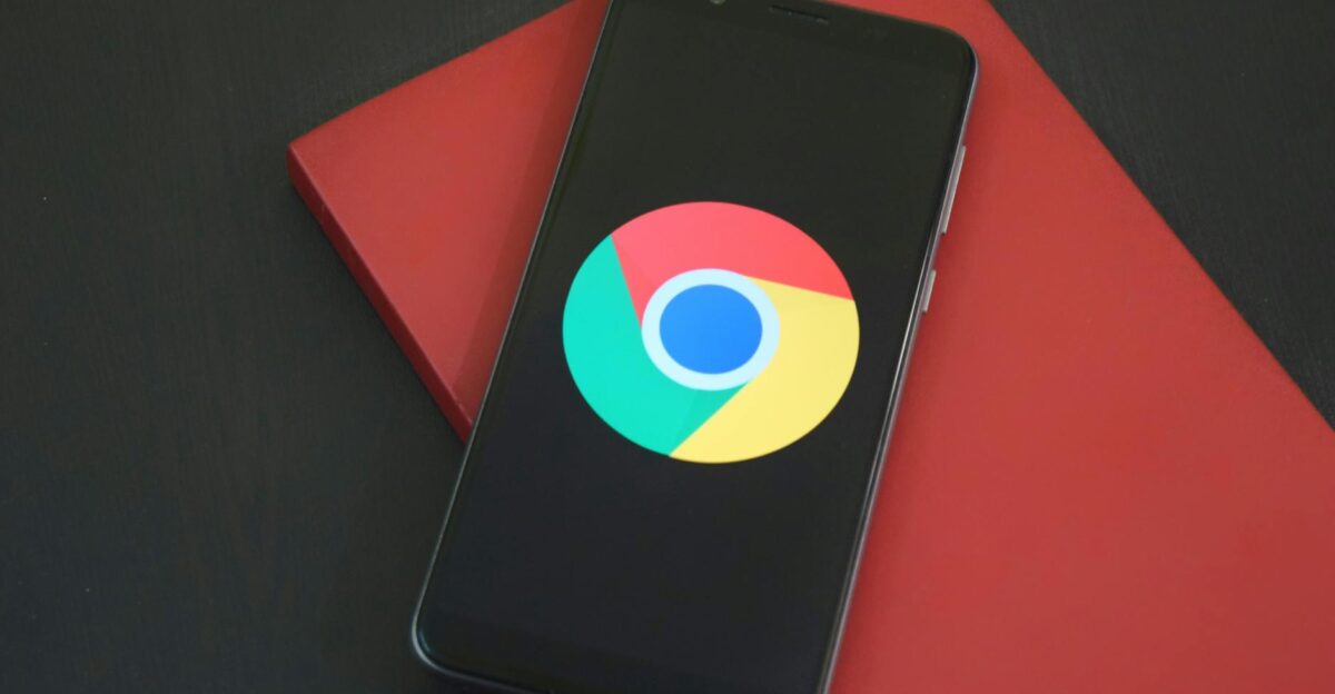 Close-up of a smartphone with Chrome browser logo on screen placed on a red notebook