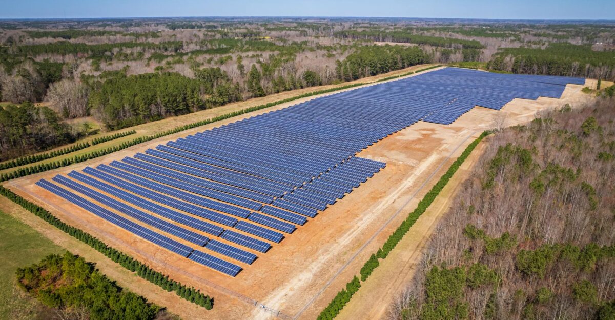 Aerial drone shot of a large solar panel farm in a rural area surrounded by forests in North Carolina