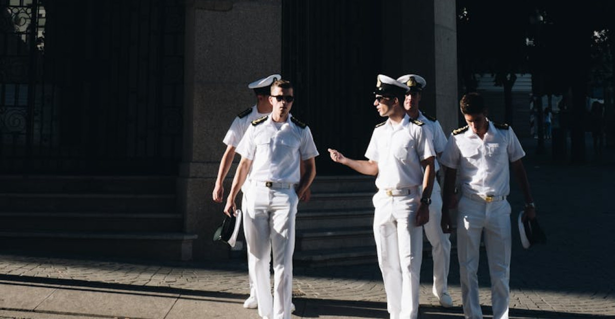 Naval officers in uniform walking together in an urban setting with a historical building in the background
