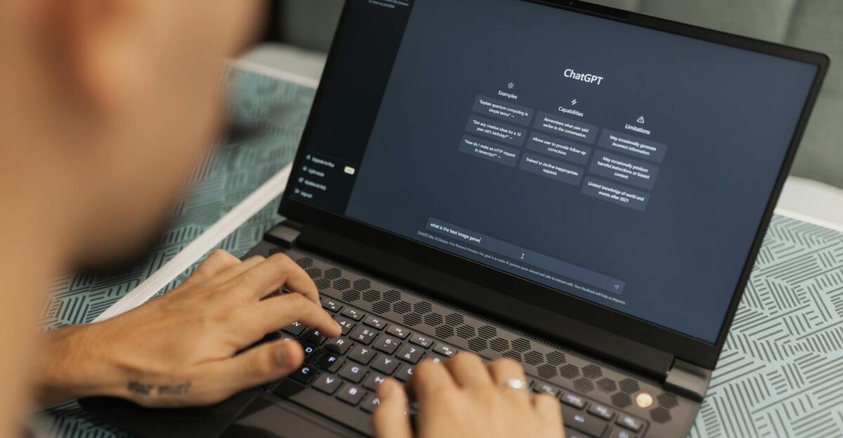Close-up of a person typing on a laptop displaying the ChatGPT interface emphasizing modern technology use