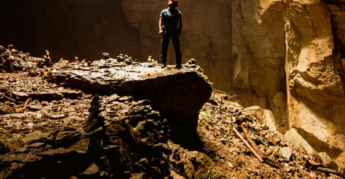 A lone explorer stands illuminated by a beam of light in a mysterious cave in Cuetzalan Mexico