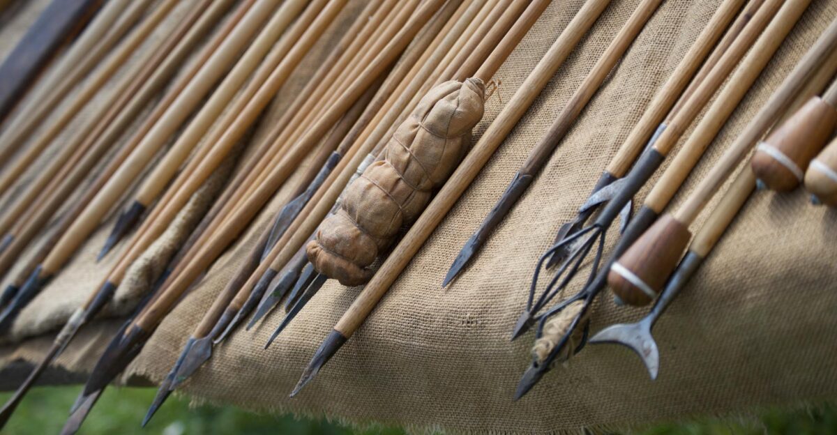 Close-up of traditional wooden javelins with distinct points laid on burlap fabric