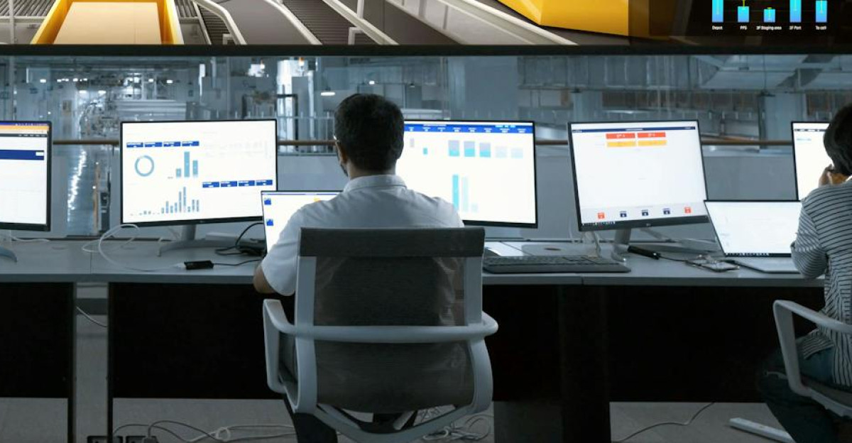 Modern control room with people monitoring large digital displays and computer systems