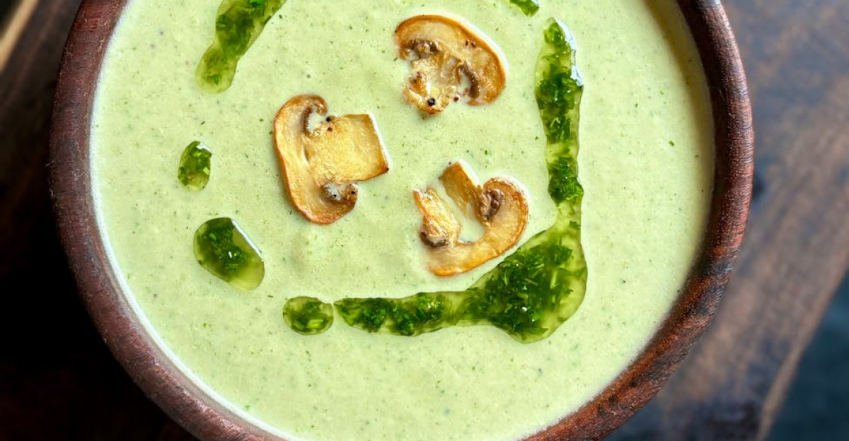 Top view of a deliciously creamy mushroom soup with herbs served in a wooden bowl