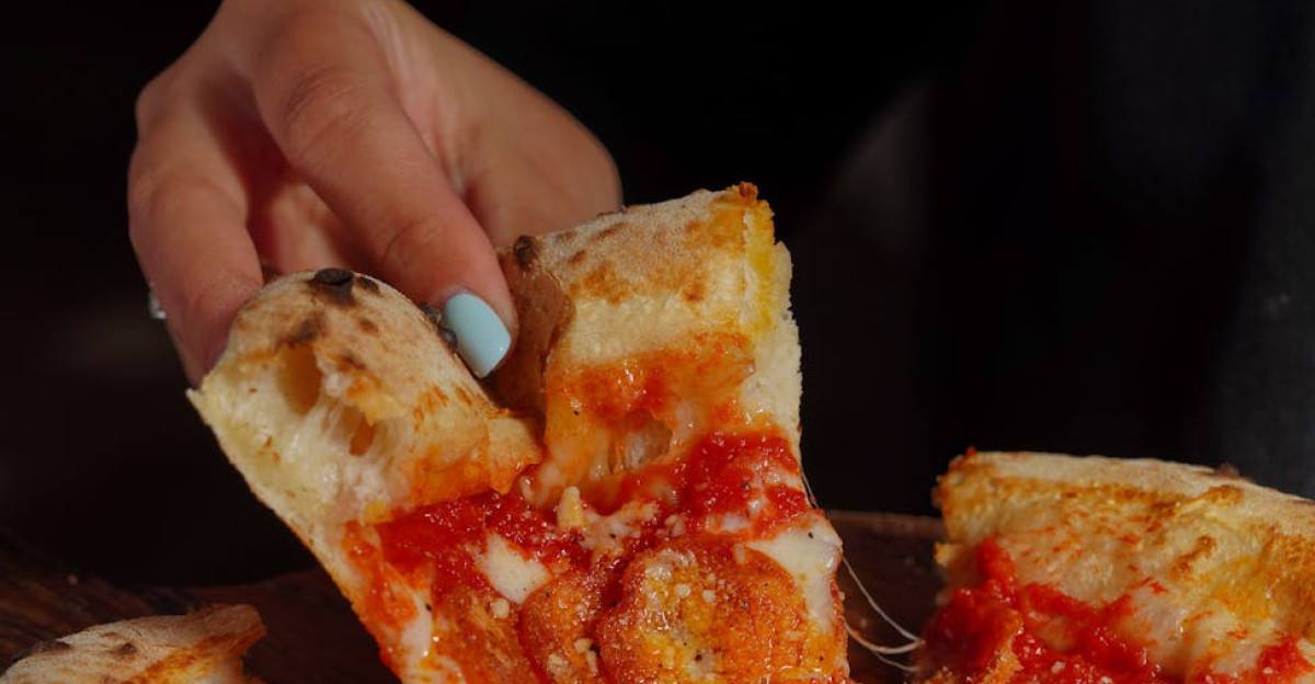 Delicious pepperoni pizza slice being lifted from a wood-fired pie with melted cheese