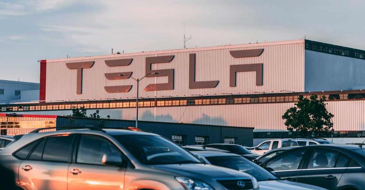 Tesla factory with parked cars during sunset showcasing modern automotive industry vibes