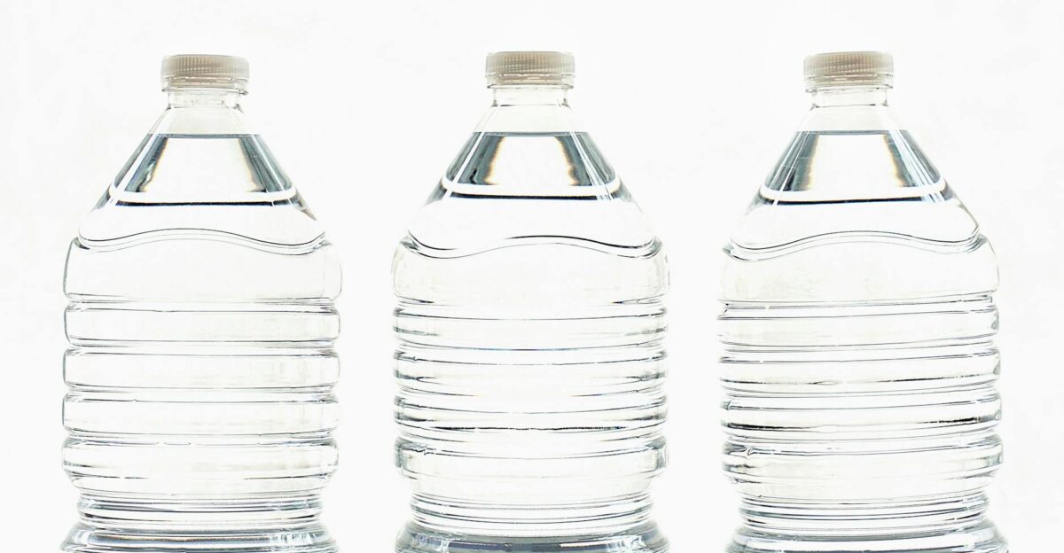 Three clear plastic bottles filled with water standing side by side