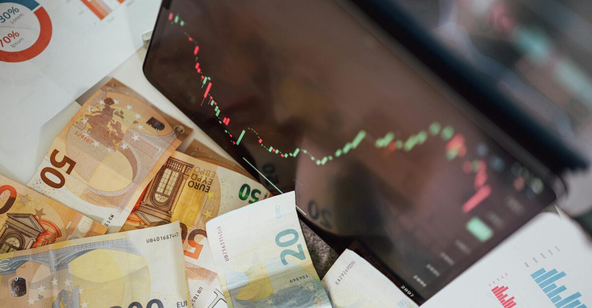 Close-up of euro banknotes with a digital stock market chart displaying a downward trend symbolizing financial volatility