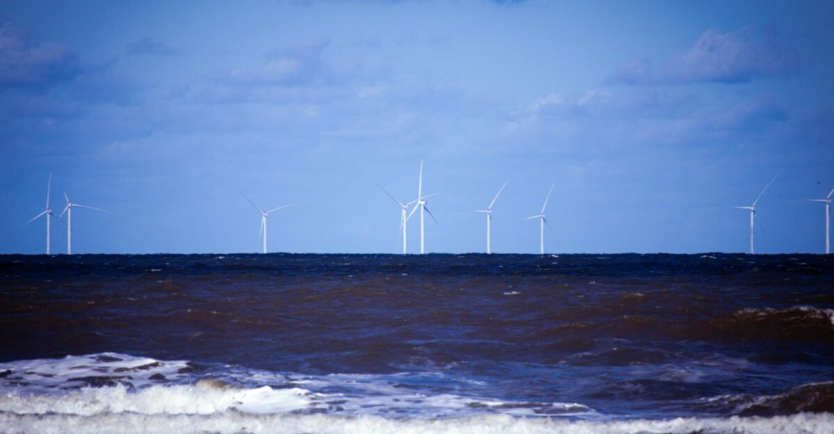 Offshore wind turbines generating sustainable energy over a calm ocean under a clear blue sky