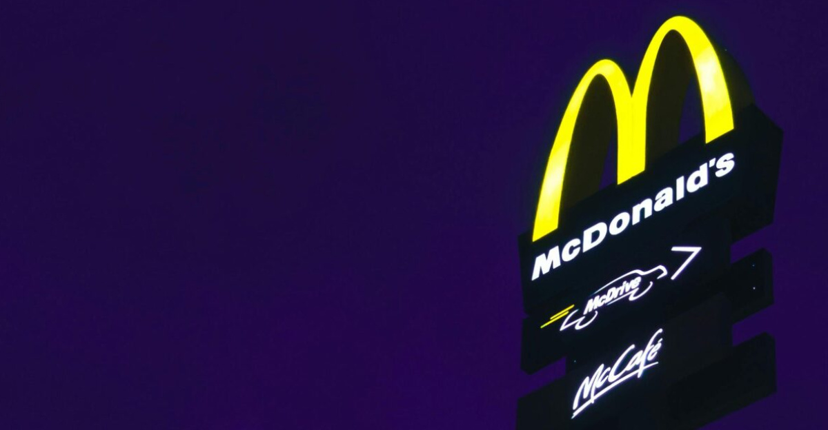 A glowing McDonald's sign stands out against a deep purple night sky.