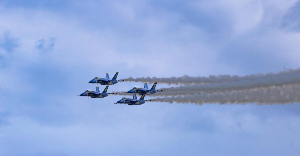 Formation of four military jets flying in a clear blue sky trailing smoke