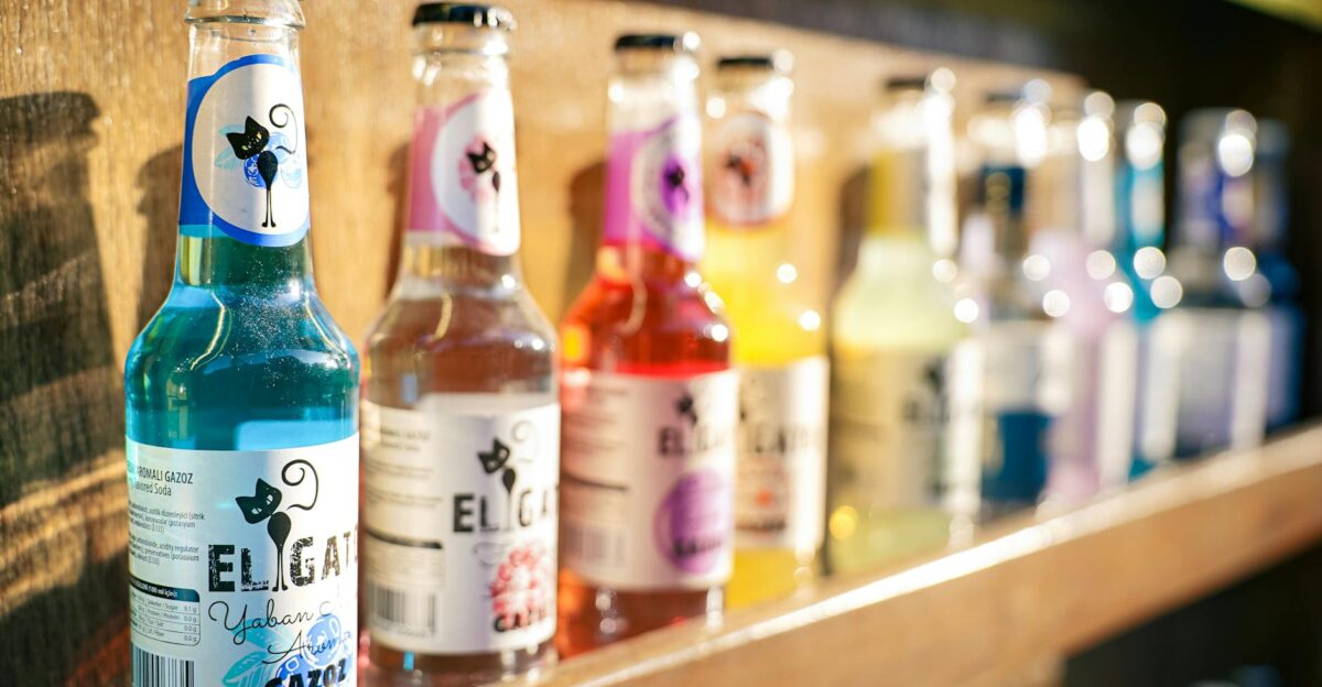 Vibrant bottles of El Gat soda lined up on a wooden shelf