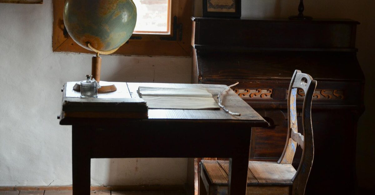 A nostalgic classroom setting featuring a globe wooden desk and piano with warm light
