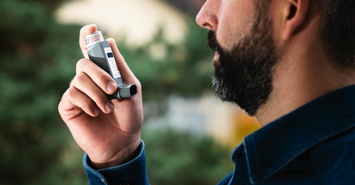 Adult man uses inhaler outdoors for asthma relief focusing on respiratory health
