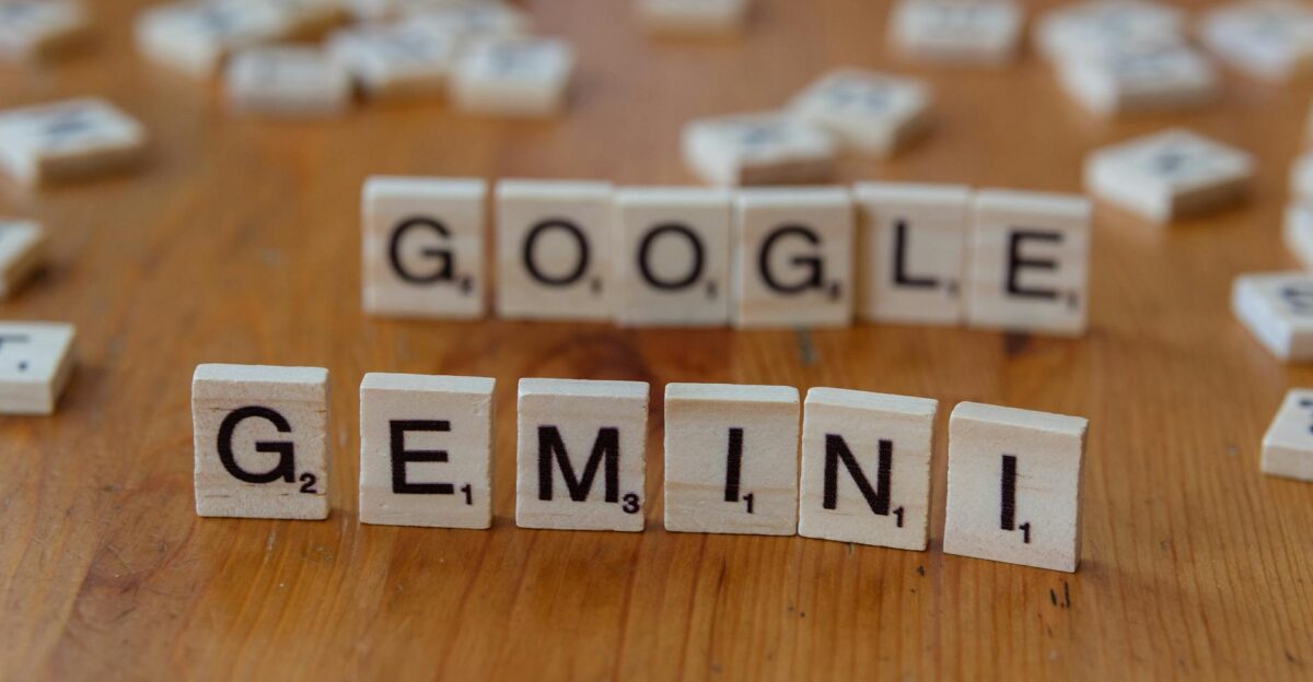 Scrabble tiles spelling out Google and Gemini on a wooden table focusing on AI concepts