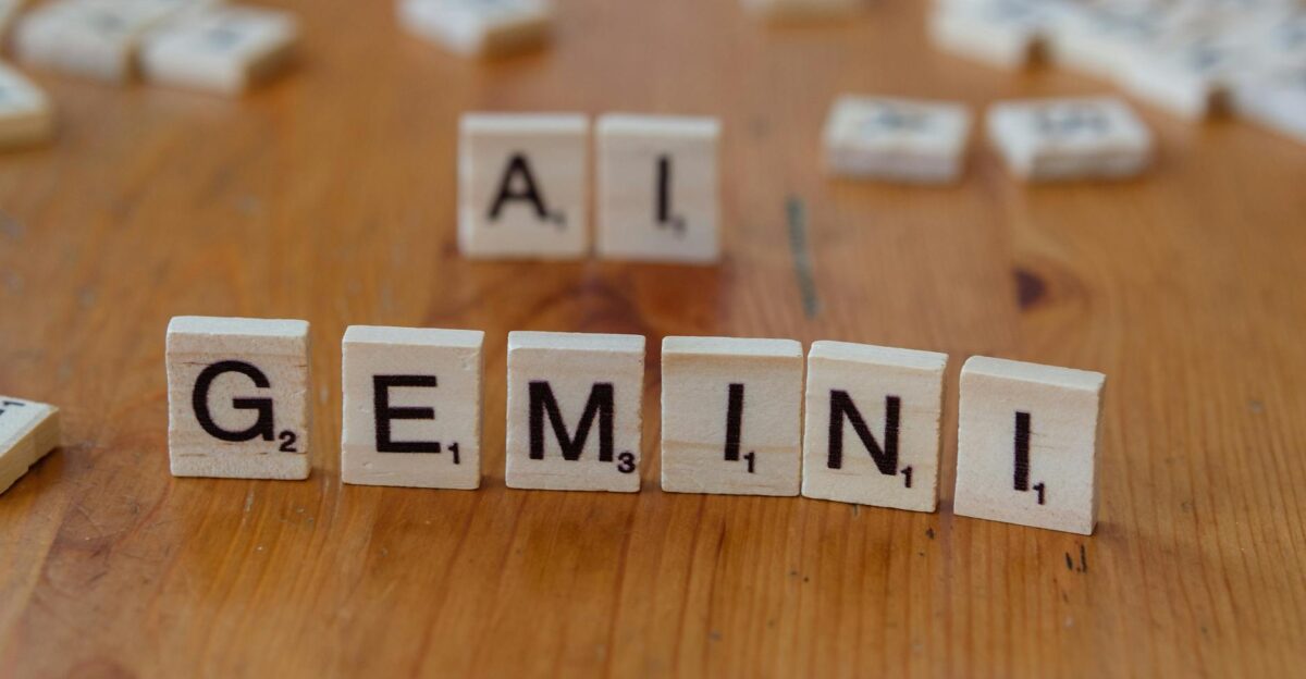 Scrabble tiles spell out the words Gemini and AI on a wooden surface symbolizing technology and communication