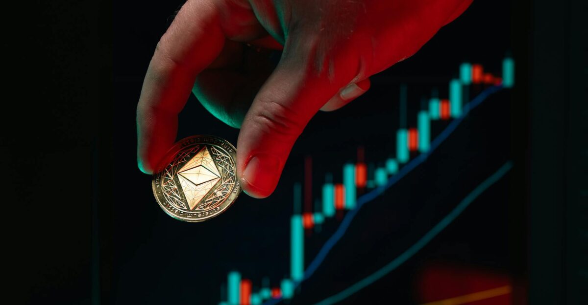 A hand holding an Ethereum coin against a rising stock market graph symbolizing cryptocurrency growth