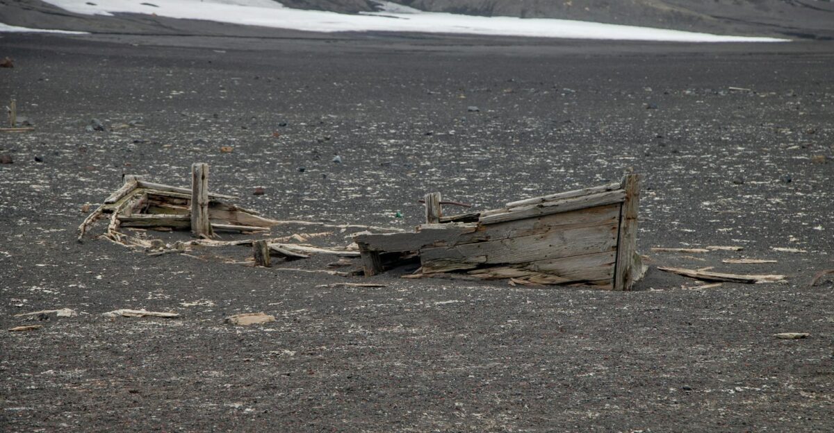 An abandoned shipwreck partially buried in a desolate Antarctic landscape showcasing historical exploration