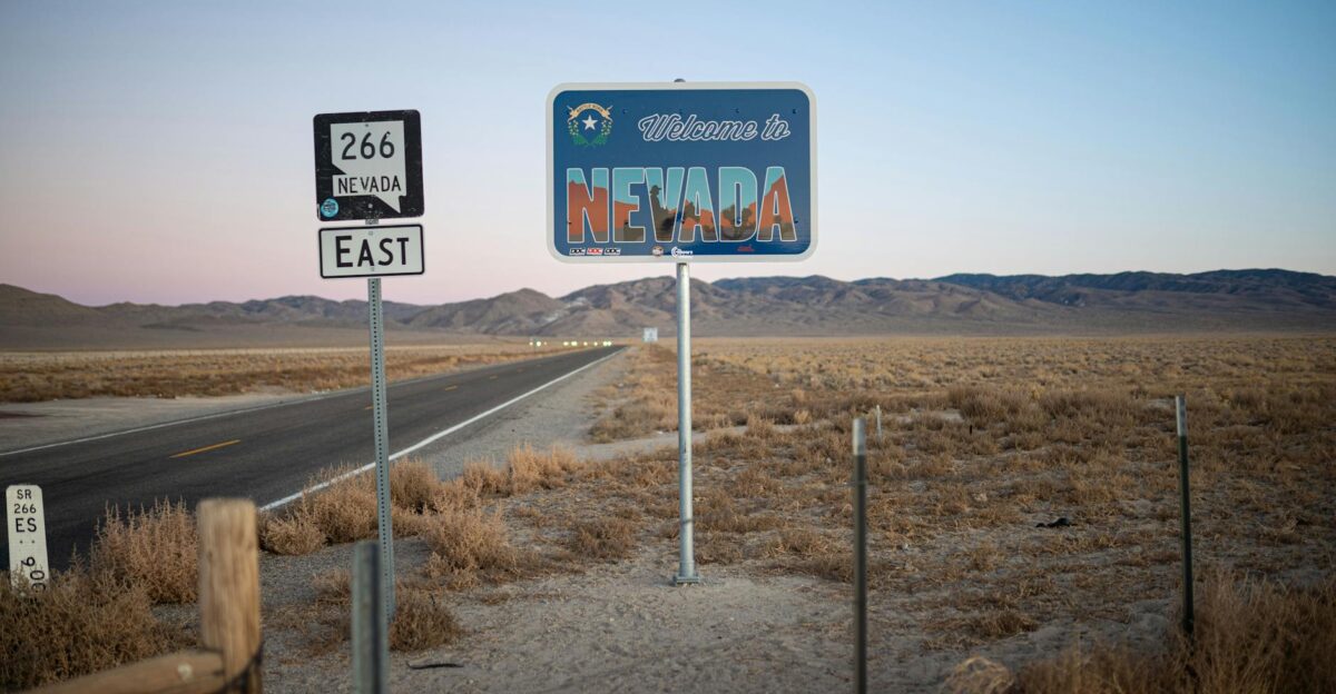 A scenic view of the Nevada desert highway at dawn with a welcome sign and empty road