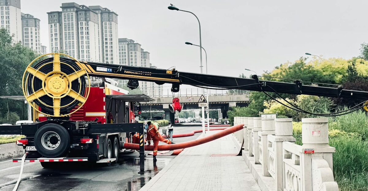 Flood management team operating machinery in urban area for water drainage