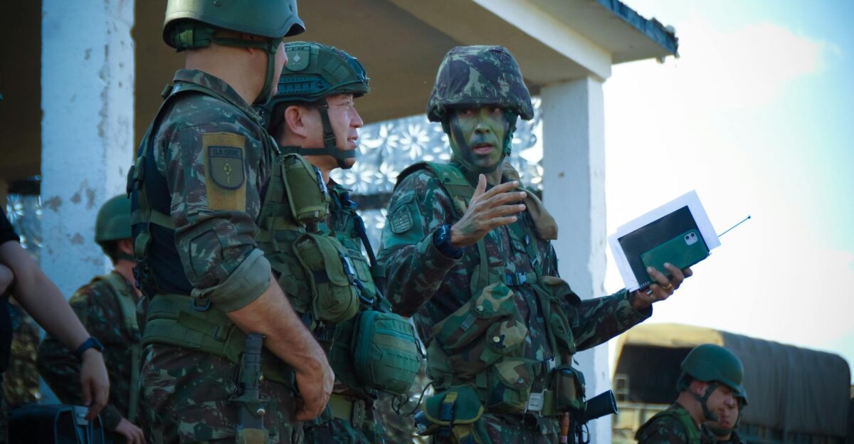 Group of soldiers in camouflage attending a briefing outdoors with tactical gear and helmets