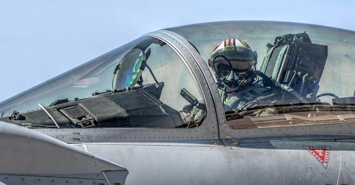 Close-up of a fighter jet pilot in the cockpit flying during a clear day