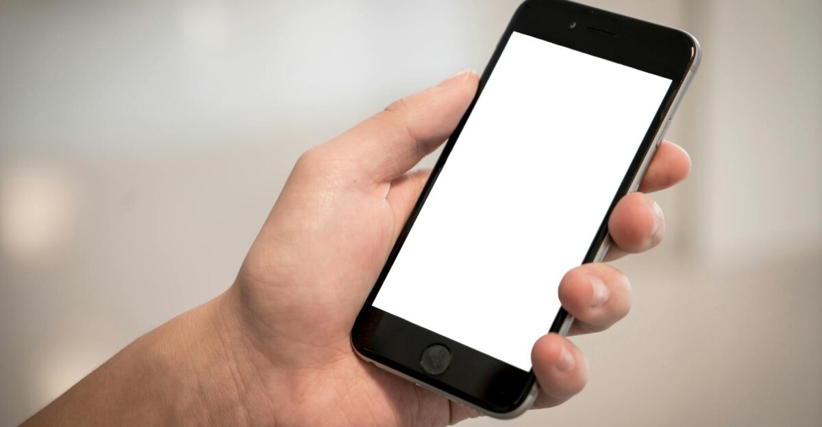 A hand holding a modern smartphone with a blank screen ideal for design mockups