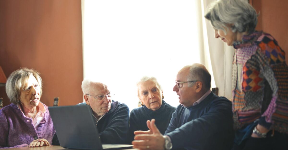 Group of senior adults discussing around a laptop in a warm indoor setting