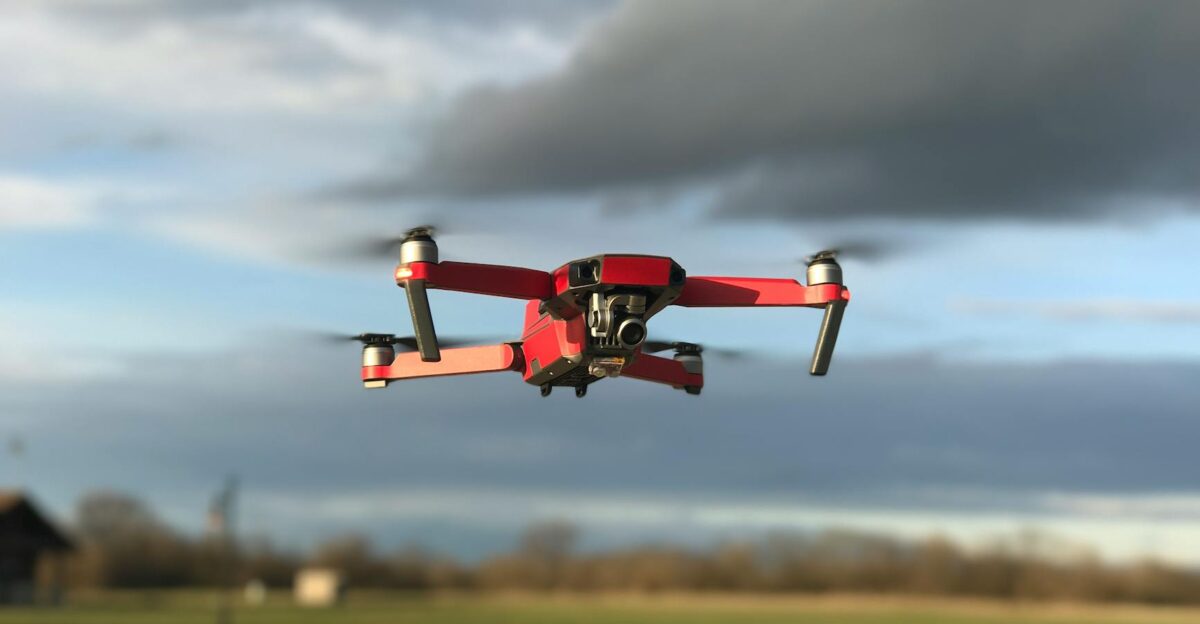Red drone hovering in the sky with dark clouds in the background showcasing modern technology