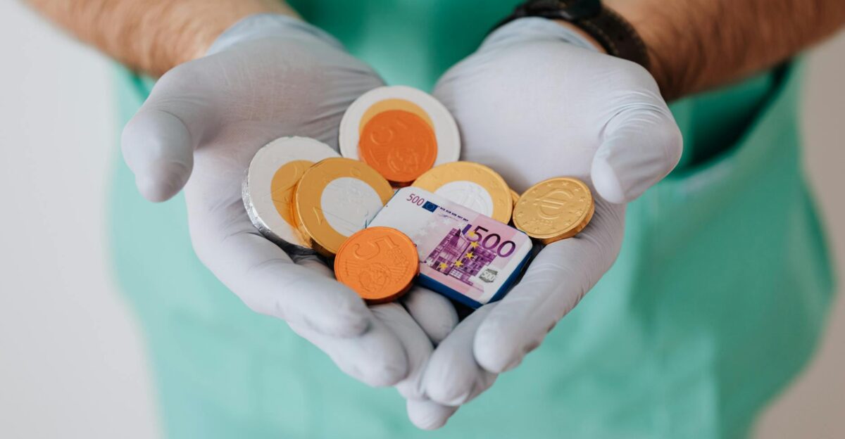 A healthcare worker with gloves holding Euro coins and a bill symbolizing medical finance