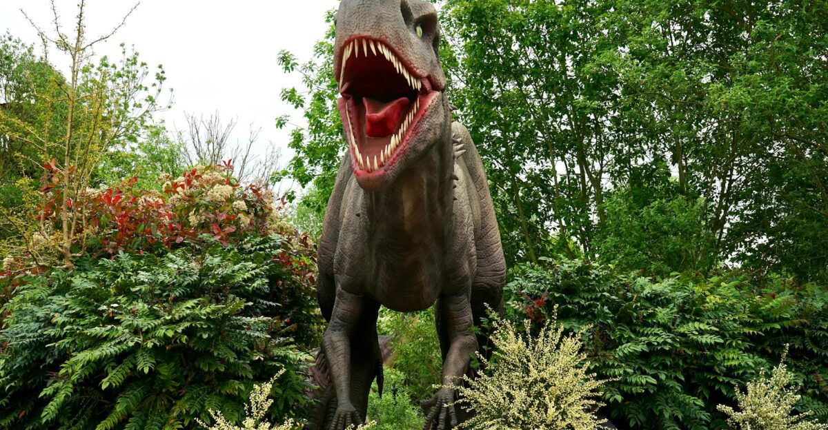 A lifelike dinosaur model surrounded by vibrant greenery in a tranquil park garden