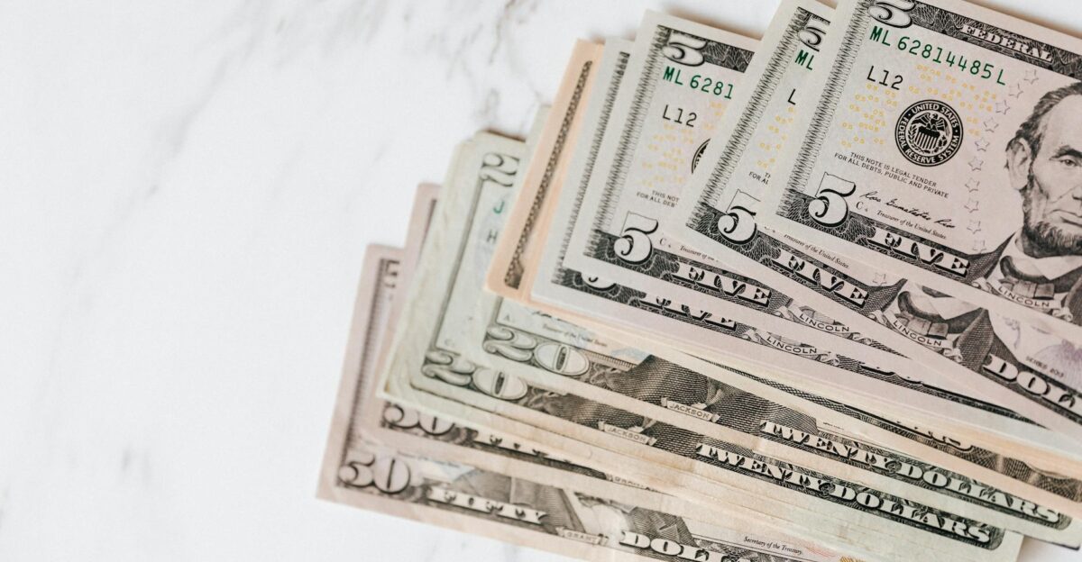 Close-up shot of various US dollar bills on a marble tabletop showcasing finance and wealth