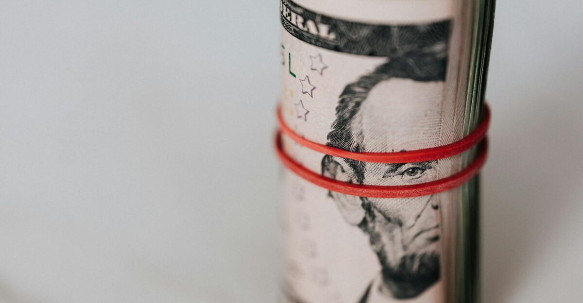Close-up of a roll of US dollars wrapped with a red rubber band focusing on financial abundance