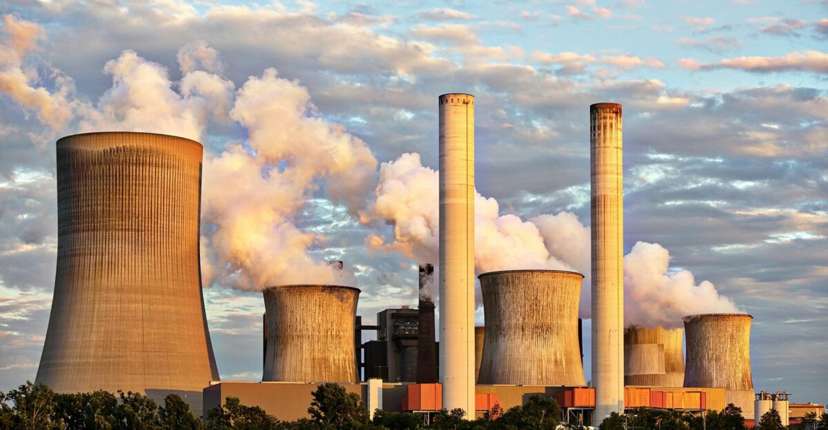 View of a power plant with smoke emissions under a cloudy sky depicting industrial energy production
