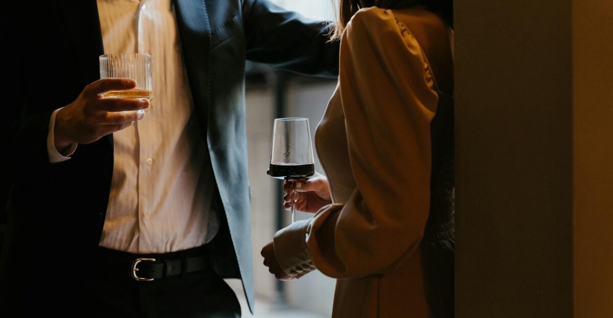 A stylishly dressed couple sharing a romantic moment with drinks at an upscale venue
