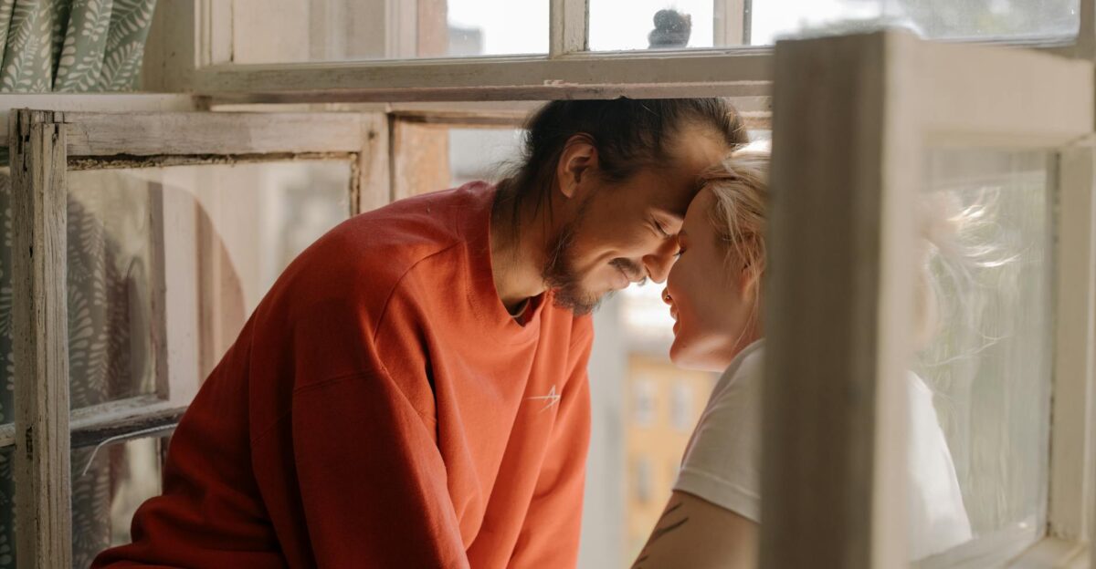 Young couple sharing a joyful moment by the window enjoying each other s company and laughter indoors