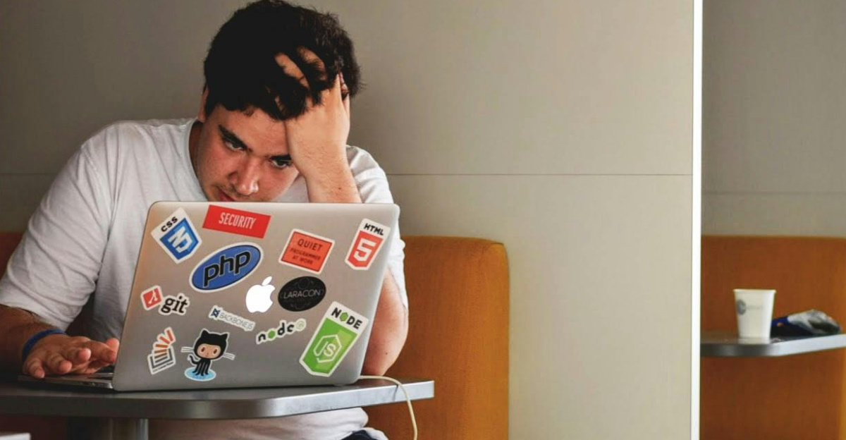 Man showing stress and frustration while working remotely on a laptop indoors.