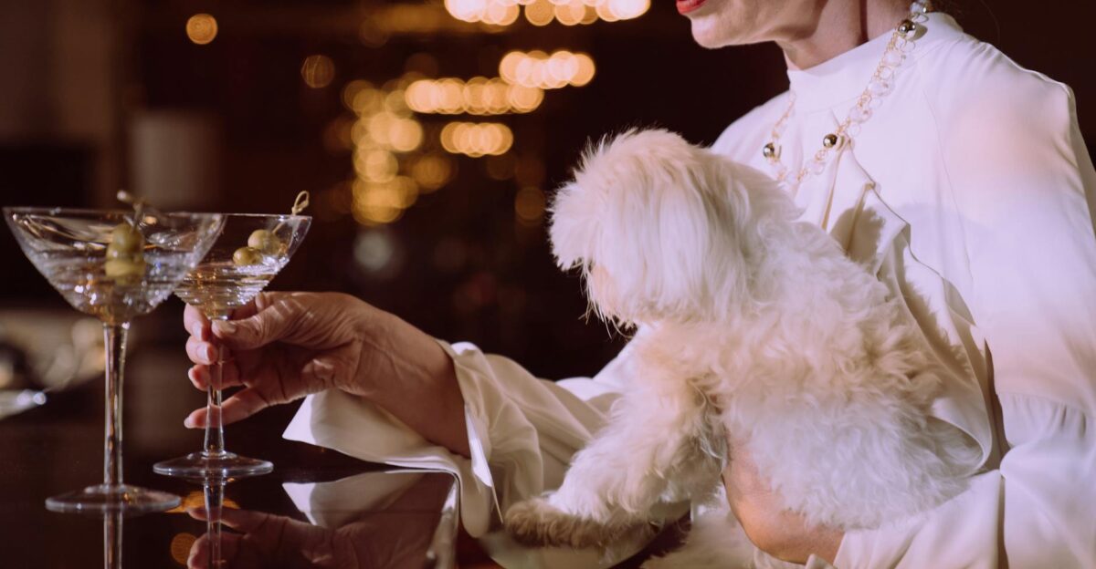 Sophisticated woman holding a white dog while enjoying cocktails at a classy bar setting