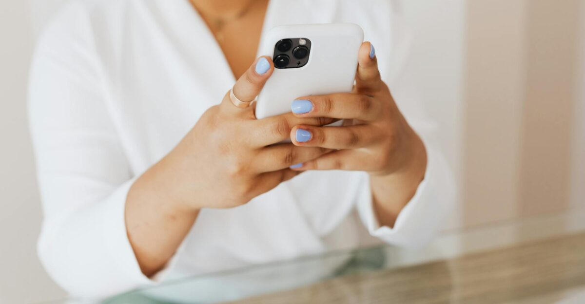 Close-up of a person holding a smartphone indoors with a focus on manicured nails