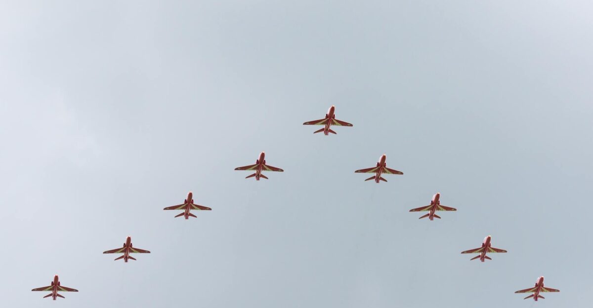 A striking image of red jets flying in a perfect V formation against a clear sky
