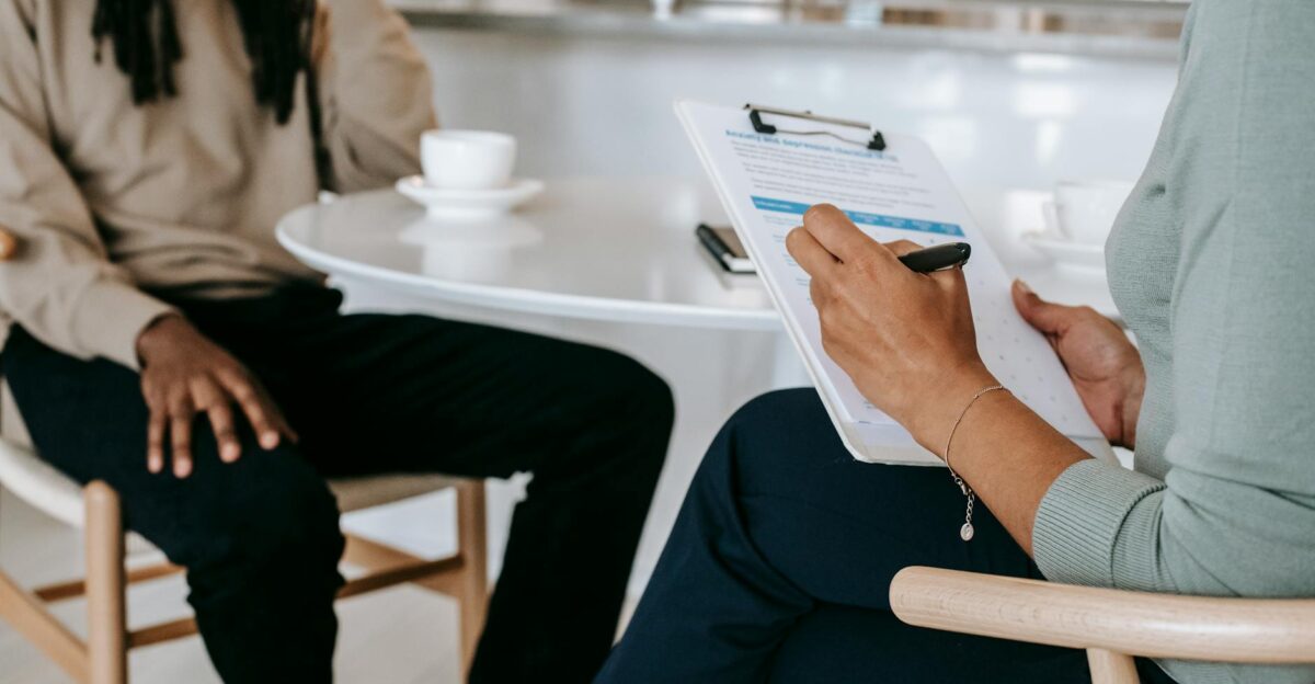Two professionals engaged in a consultation one taking notes on a clipboard