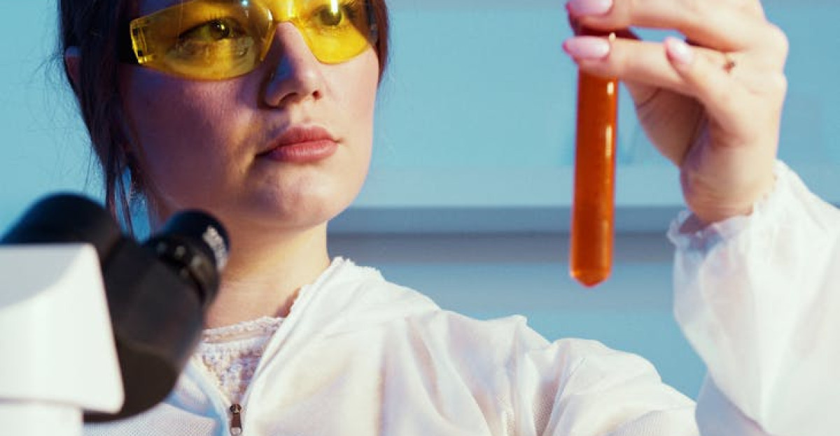 A female scientist in protective gear analyzing a test tube in a laboratory setting